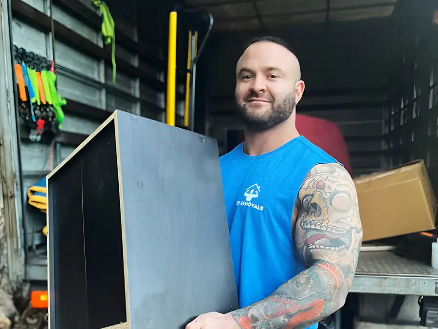 A Fit Removals mover loading a cabinet into the truck